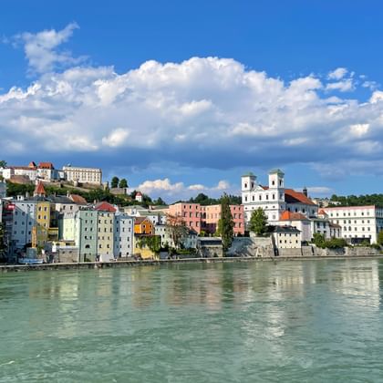 Panoramisch uitzicht op Passau's kleurrijke historische gebouwen langs de Donau, met barokke architectuur en opvallende witte kerk.