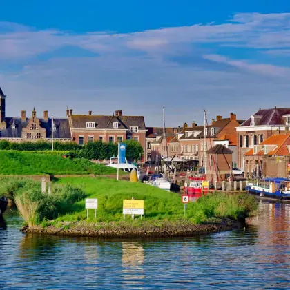 Schilderachtig havengezicht van Willemstad, Zeeland met historische kerktoren, kleurrijke Nederlandse huizen, boten aan de kade en groen eiland.