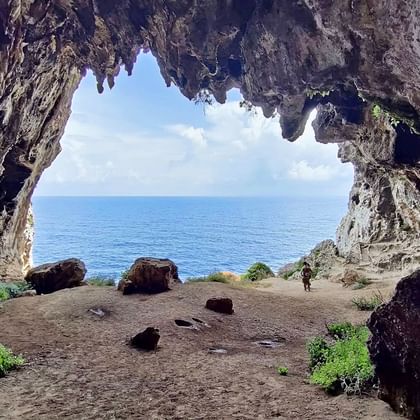 Binnenaanzicht van de Cipollane grot in Apulië met uitzicht op de blauwe zee door de grotopening, rotsige wanden en groene vegetatie zichtbaar.