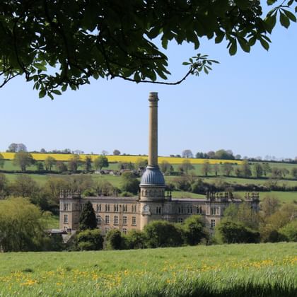 Bliss Mill met kenmerkende koepel en hoge schoorsteen in Chipping Norton, Cotswolds, omgeven door groene velden en gele koolzaadvelden.