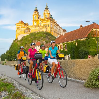 Cyclists cycle past Melk Abbey