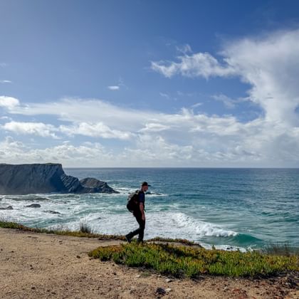Wandelaar met rugzak op kustklif met uitzicht op de Atlantische Oceaan op de Portugese Camino van Porto naar Santiago de Compostela.