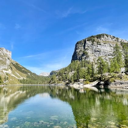 Kristalheldere bergmeer in het Ausseerland dat dramatische kalkstenen kliffen en groene bossen weerkaatst onder een heldere blauwe hemel.