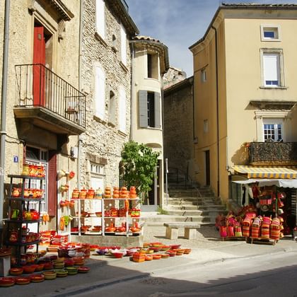 Smalle stenen straat in de Provence met traditionele gebouwen, marktkramen met aardewerk en lokale producten, rode luiken.