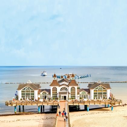 Historische pier van Sellin die uitsteekt in de Oostzee op Rügen. Wit paviljoen met sierlijke architectuur op houten pier, zandstrand op de voorgrond.