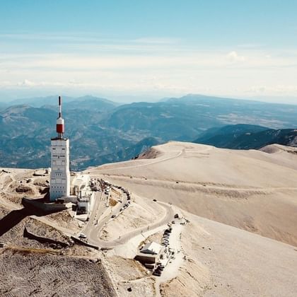 Top van Mont Ventoux in de Provence met witte kalkstenen piek, weerstatietoren en bergketens op de achtergrond.