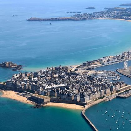 Luchtfoto van de ommuurde stad Saint-Malo aan de Bretonse kust, met historische vestingwerken omringd door turquoise water en zandstranden.
