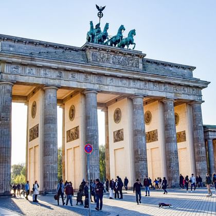 De Brandenburger Tor in Berlijn met zijn neoklassieke zuilen en de Quadriga-sculptuur bovenop. Toeristen verzamelen zich voor de verlichte poort.