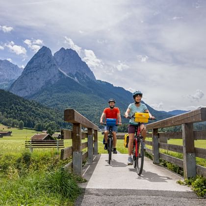 Cyclists crossing a bridge, mountains in the background