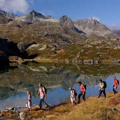 Seven hikers walk beside the lake on the Albula.