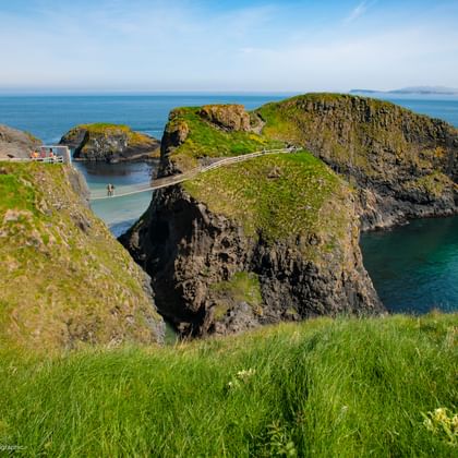 Carrick-a-Rede touwbrug verbindt groene kustrotsen over turquoise water in County Antrim, Noord-Ierland.