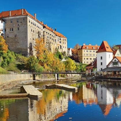 Schilderachtig uitzicht op Krumlovs oude stad met middeleeuws kasteel, kleurrijke gebouwen met rode daken en rivier die de architectuur weerkaatst.