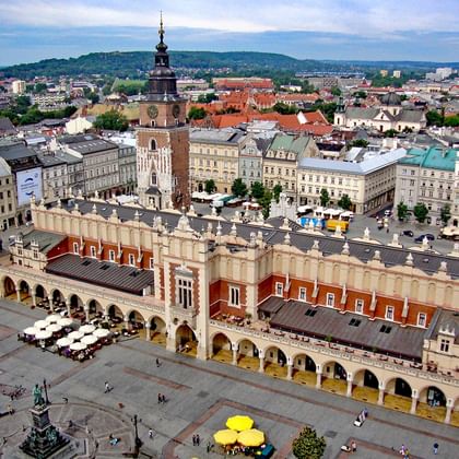Luchtfoto van Krakaus Hoofdmarktplein met de Renaissance Lakenhallen met boogvormige galerijen en de Stadhuis toren op de achtergrond.