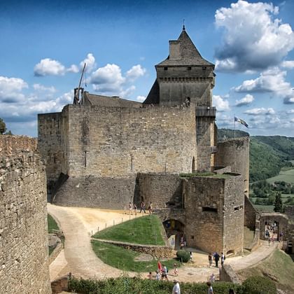 Middeleeuws Château de Castelnau met stenen muren en toren met uitzicht op groene vallei in Périgord Noir. Bezoekers op binnenplaats.