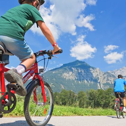 Son and father on beautiful asphalted cycle paths with mountain panorama in the background