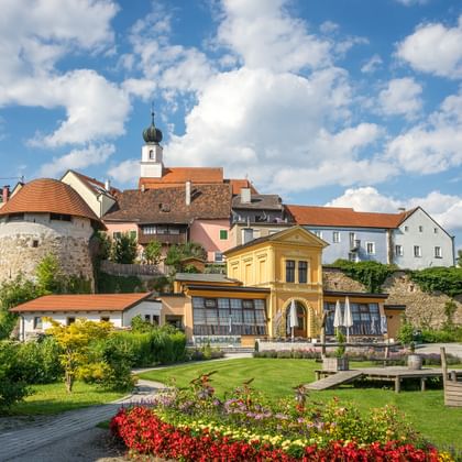 Schilderachtig uitzicht op Schärding met kleurrijke historische gebouwen, kerktoren met uikoepel, middeleeuwse stenen muren en tuin.