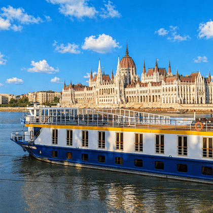 Blauw-wit riviercruiseschip MS Katharina afgemeerd aan de Donau met het Hongaarse parlementsgebouw op de achtergrond.