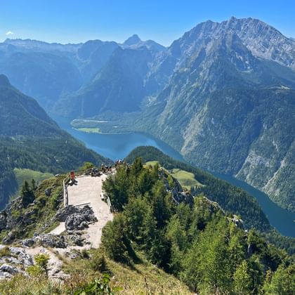 Panoramisch uitzicht vanaf Jenner berg met Königssee meer tussen steile Alpentoppen. Bezoekers verzamelen op rotsachtig platform.