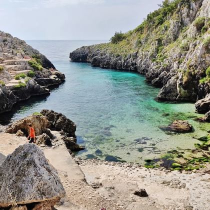Afgelegen Acquaviva strand baai in Apulië met kristalhelder turquoise water omgeven door kalkstenen kliffen en mediterrane vegetatie.