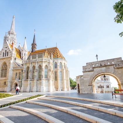 Gotische Matthiaskerk met kleurrijk pannendak en witte stenen muren naast het middeleeuwse Vissersbastion met bogen in Boedapest.