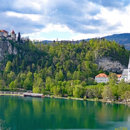 Meer van Bled in Slovenië met smaragdgroen water, middeleeuws kasteel op klif, witte kerk met toren en Julische Alpen.